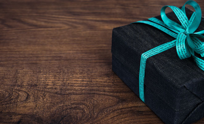 dark blue present wrapped with teal bow, on wooden table