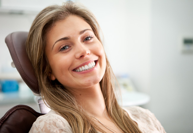 brunette woman sits in a dental chair before getting her wisdom teeth removed